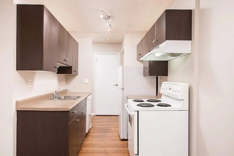 A small kitchen with white appliances and brown cabinets.