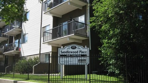A sign for Sandlewood Place is in front of a building.