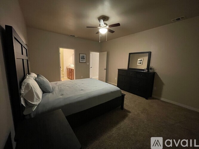 A bedroom with a bed, dresser, and ceiling fan.