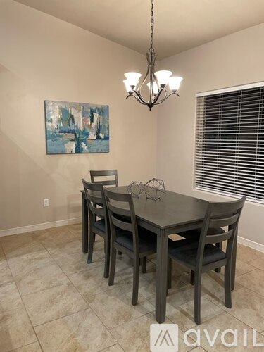 A dining room with a table and chairs and a painting on the wall.