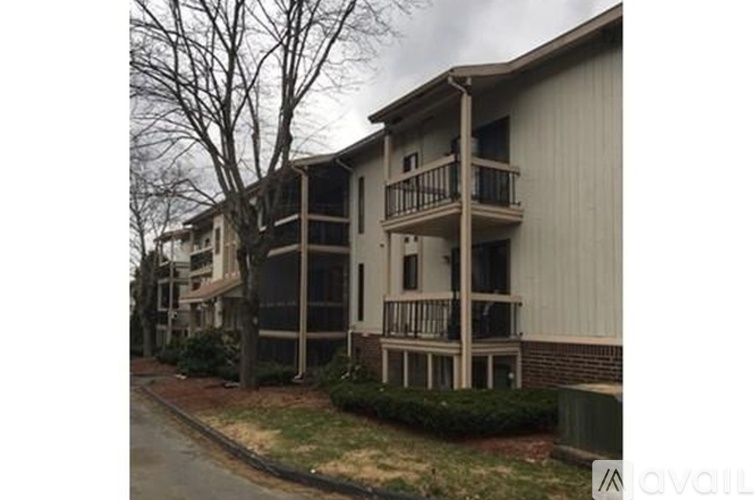 Apartment building with a balcony and a tree in front.