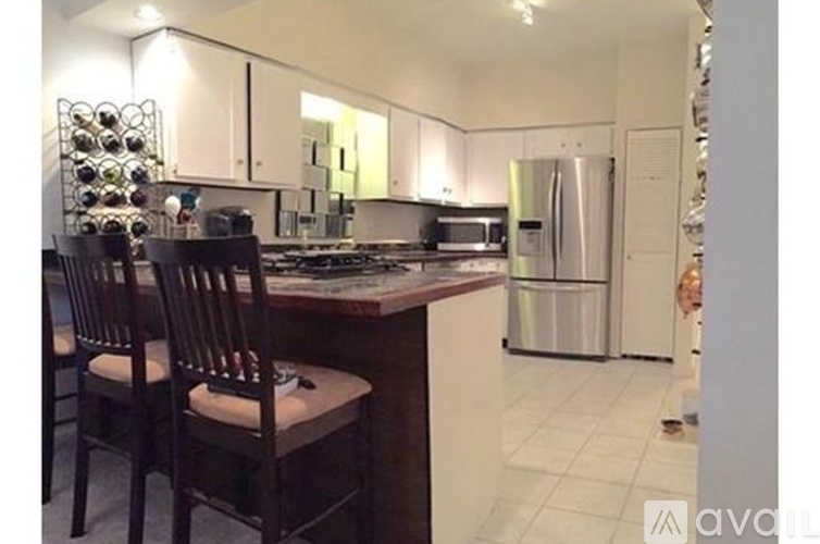 A kitchen with a refrigerator, stove, and chairs.