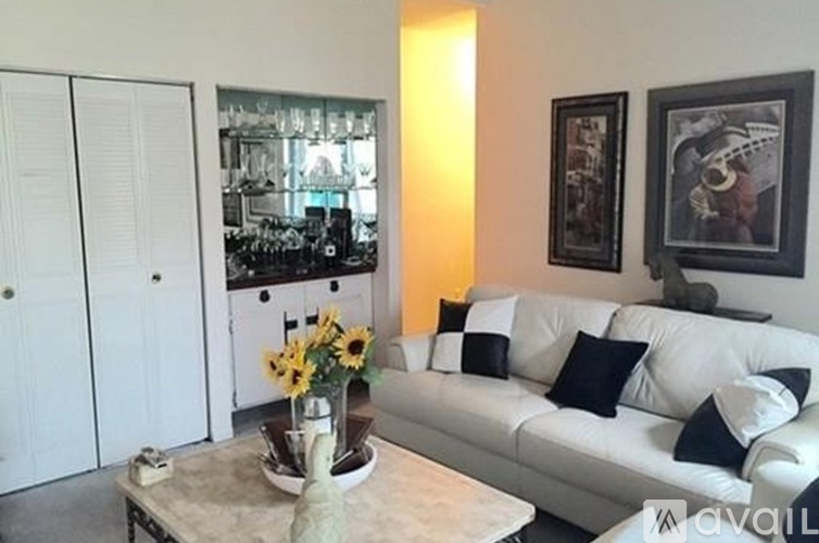 A living room with a white couch and a vase of sunflowers on the coffee table.