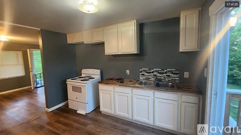 A kitchen with white cabinets and a wood floor.