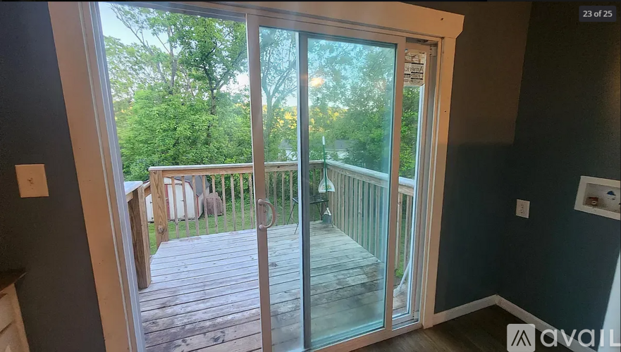 A balcony with glass doors leading to a deck surrounded by trees.