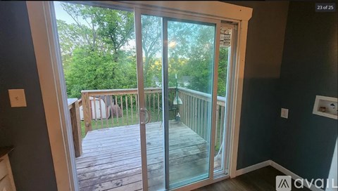 A balcony with glass doors leading to a deck surrounded by trees.