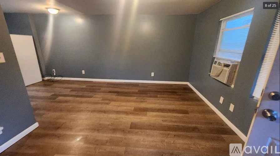 A room with wooden flooring and a window with blinds.