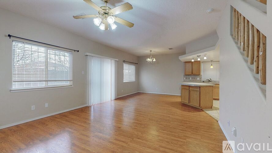 A spacious room with wooden floors and a ceiling fan.