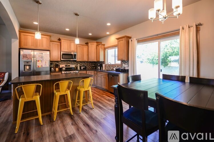 A kitchen with wooden floors and a bar area with yellow chairs.