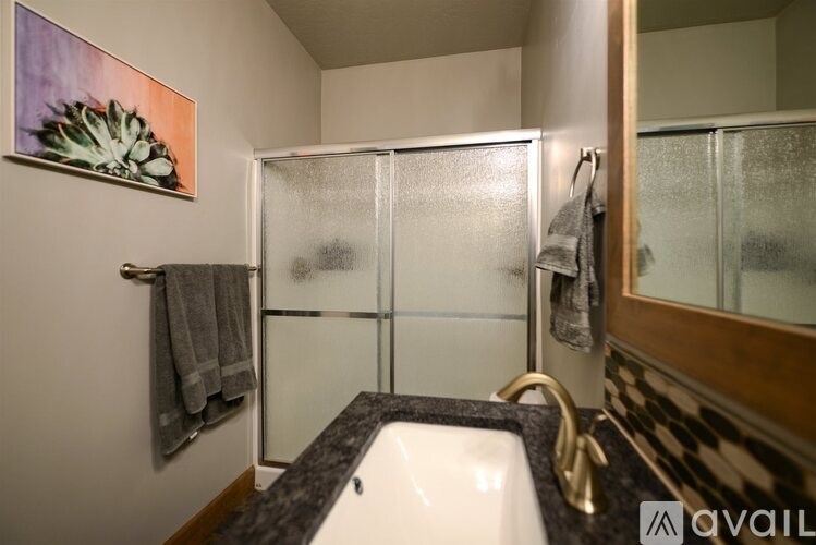 A bathroom with a white sink and a glass shower door.