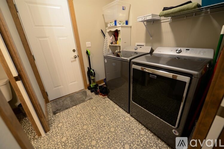 A kitchen with a black and white floor, a white door, a black vacuum cleaner, and a black oven.