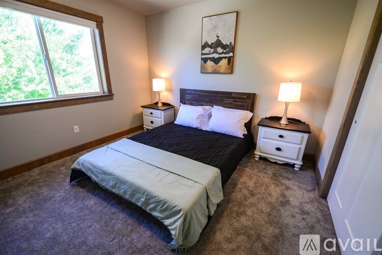 A bedroom with a large bed, two nightstands, and a window.