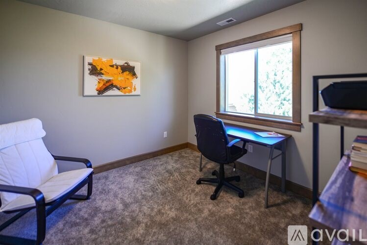 A room with a chair, a desk, and a painting on the wall.