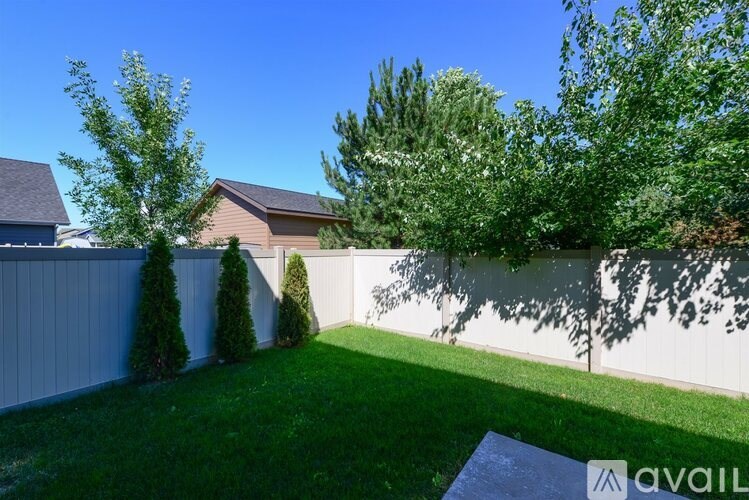 A backyard with a white fence and green grass.