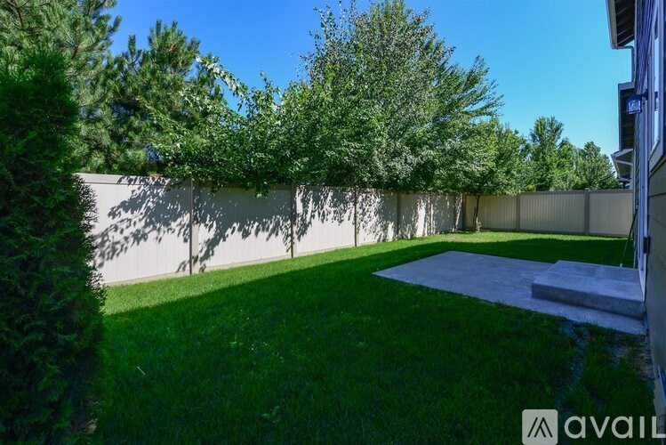 A backyard with a well-maintained lawn and a white fence.