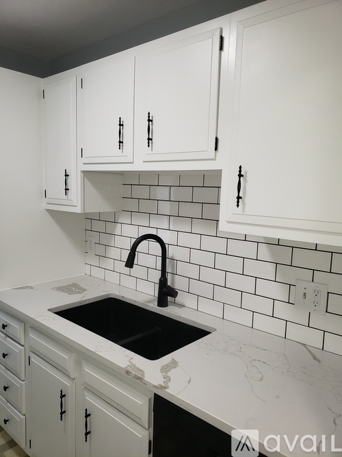 A kitchen with white cabinets and a black sink.