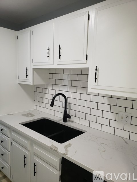 A kitchen with white cabinets and a black sink.