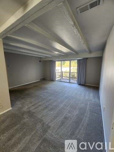 A spacious room with a carpeted floor and a slanted ceiling.