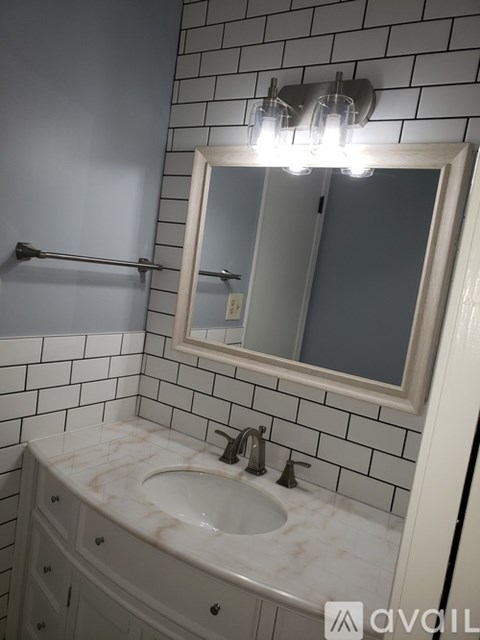 A bathroom with a marble sink and a mirror above it.