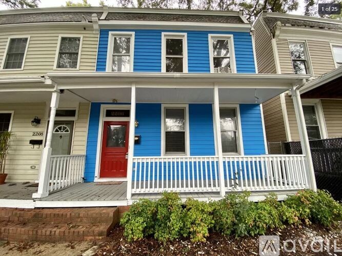 A blue and white house with a red door and white porch.