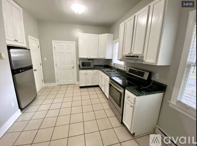 A kitchen with white cabinets and black appliances.