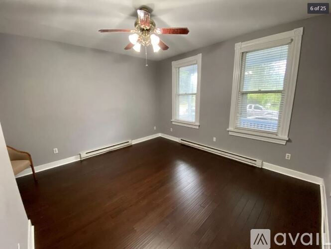 A room with a ceiling fan and two windows.