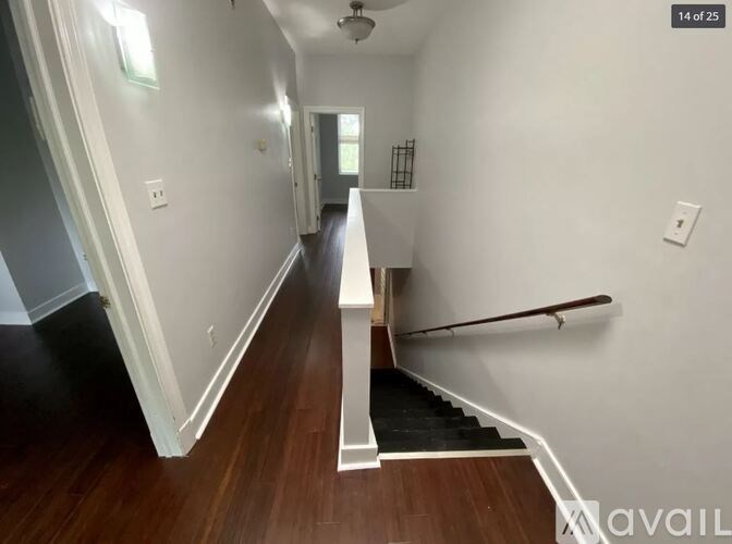 A hallway with a staircase and a white railing.