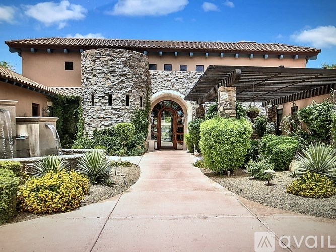A house with a stone wall and a pathway leading to the entrance.