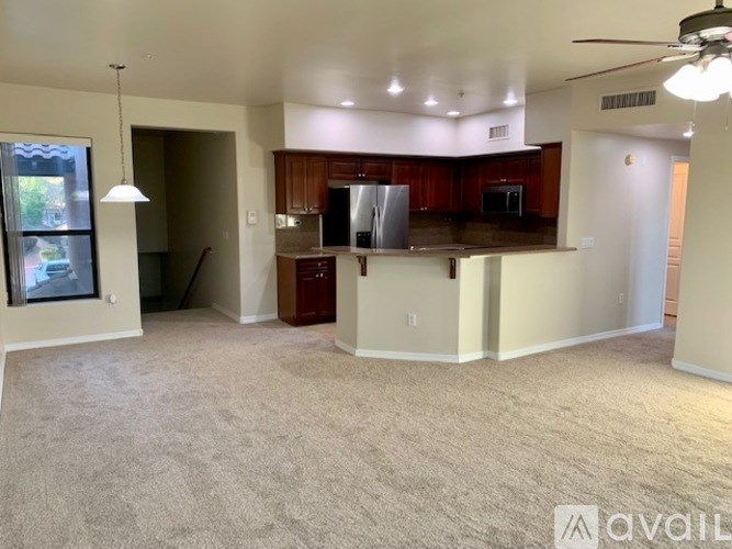 A spacious living room with a kitchen area in the background.