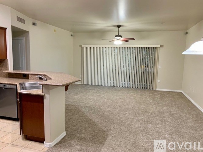 A kitchen area with a sink, dishwasher, and a fan.