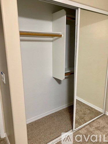 A white closet with a mirrored door and a shelf.