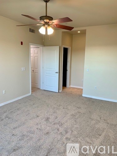 A room with a ceiling fan and carpeted floor.