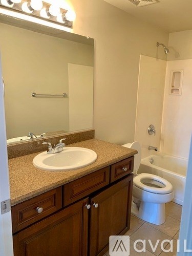 A bathroom with a sink, mirror, toilet and shower.