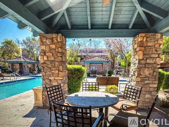 A patio with a table and chairs overlooking a pool.