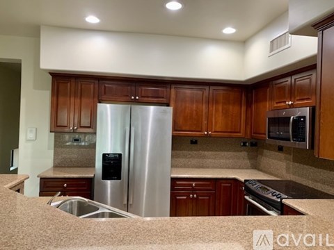 A kitchen with a stainless steel refrigerator and wooden cabinets.