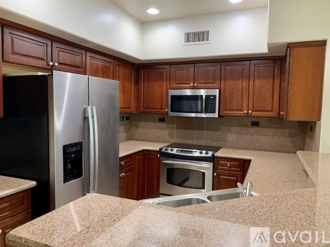 A kitchen with brown cabinets and a stainless steel refrigerator.