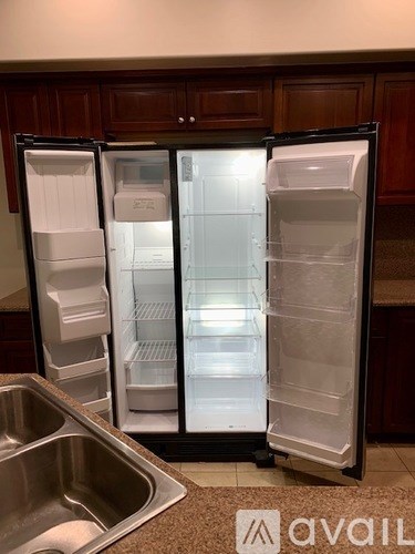 A white fridge with the door open is in a kitchen.