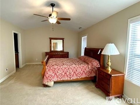 A bedroom with a bed, dresser, and ceiling fan.
