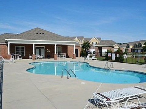 A swimming pool in front of a house with a fence around it.