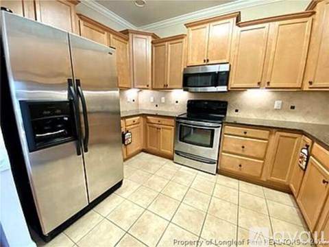 A kitchen with wooden cabinets and a stainless steel refrigerator.