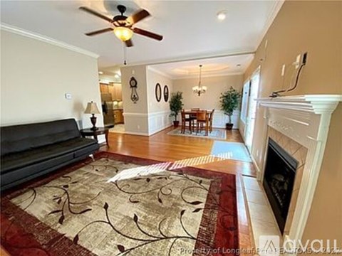 A living room with a black couch and a rug with a design on it.
