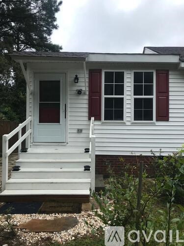 A small white house with a red door and a window with red shutters.