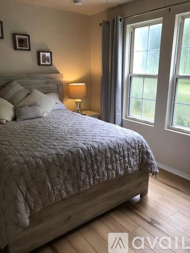 A bedroom with a large bed and a window with curtains.