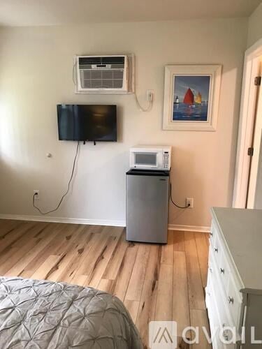 A room with a bed, a microwave, a TV, and a painting on the wall.