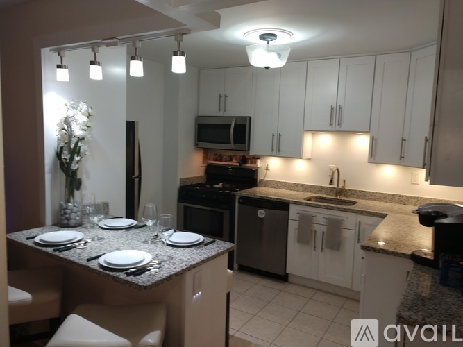A kitchen with a table set for two with plates and glasses.