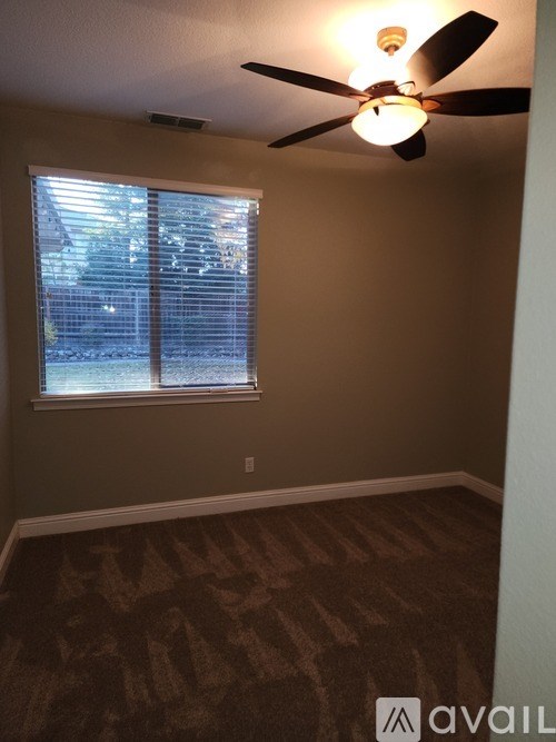 A room with a ceiling fan and a window with blinds.