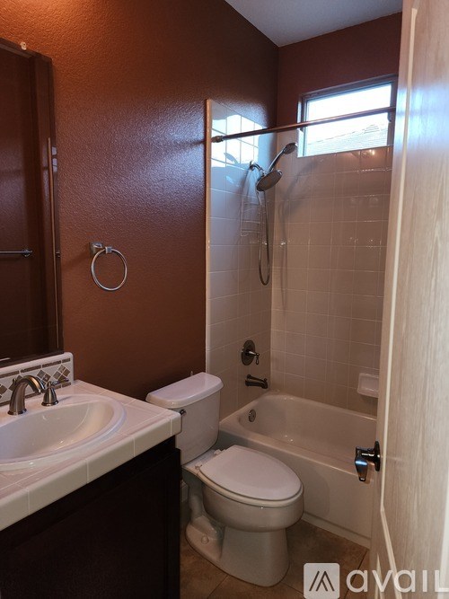 A bathroom with brown walls has a toilet, sink, and bathtub.