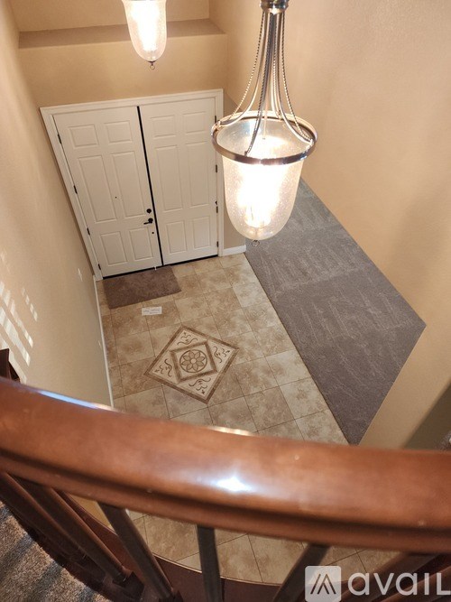 A chandelier hangs over a pair of white doors in a hallway.