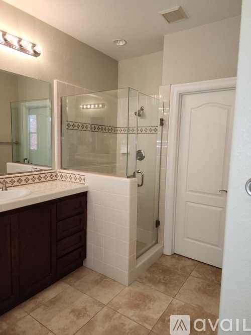 A bathroom with a glass shower door and a white door.