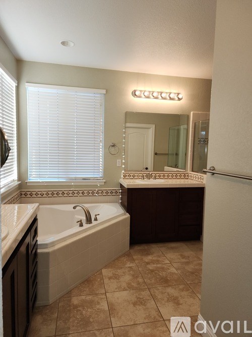 A bathroom with a tub, sink, and mirror.